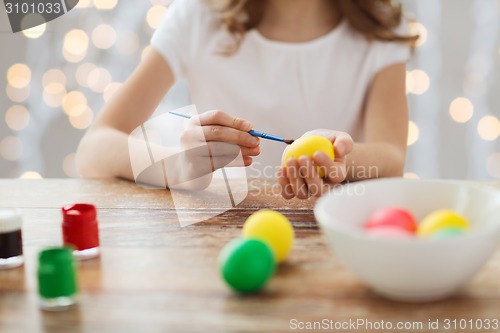 Image of close up of girl with brush coloring easter eggs