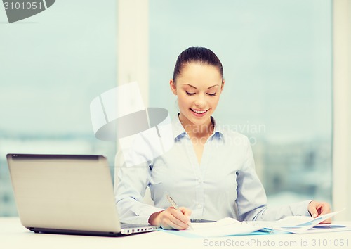 Image of businesswoman with laptop and charts in office