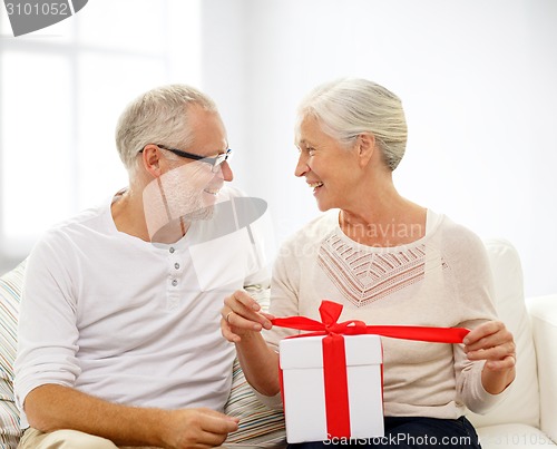 Image of happy senior couple with gift box at home