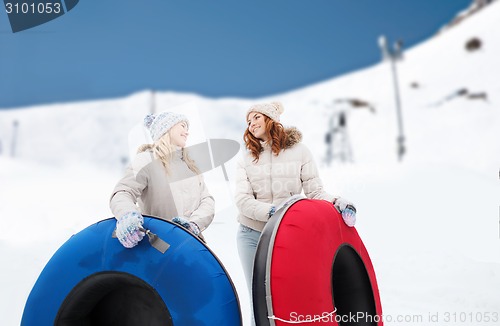 Image of happy girl friends with snow tubes outdoors