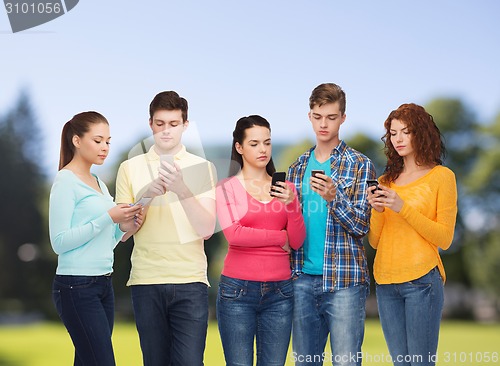 Image of group of serious teenagers with smartphones