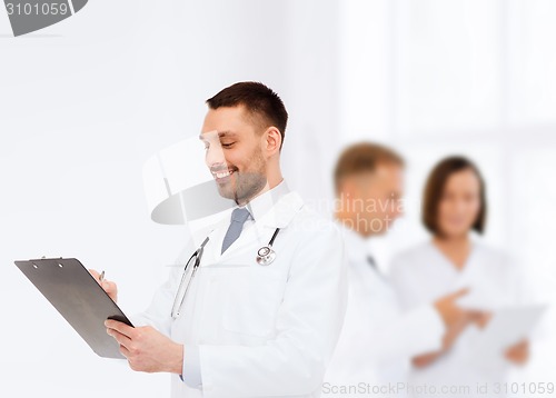 Image of smiling male doctor with clipboard and stethoscope