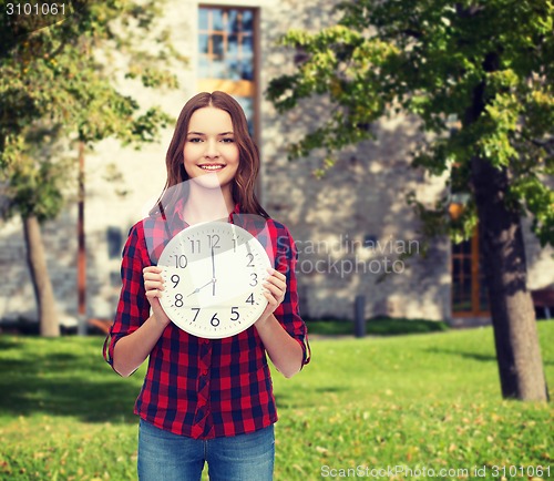 Image of young woman in casual clothes with wall clock