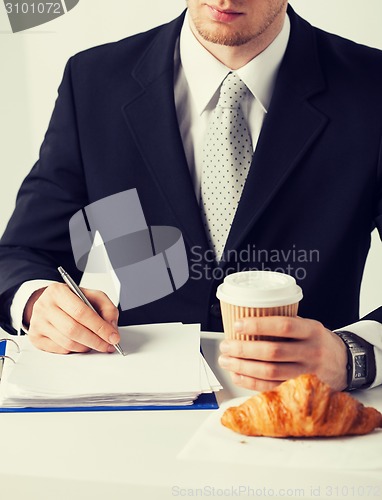 Image of businessman with coffee writing something