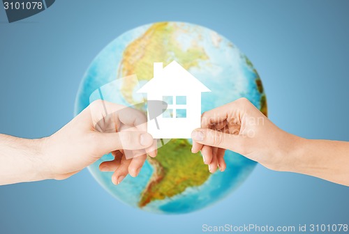 Image of couple hands holding green house over earth globe