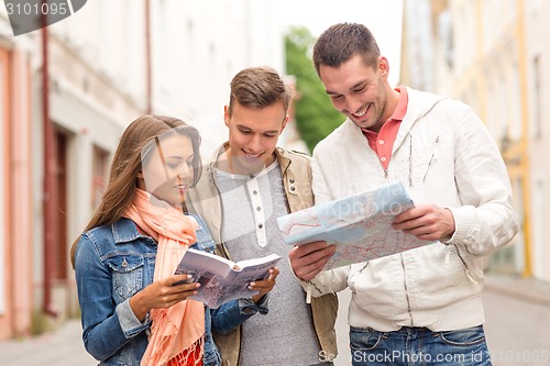 Image of group of smiling friends with city guide and map