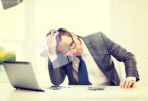 Image of businessman with computer, papers and calculator