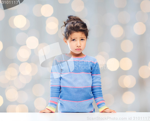 Image of sad little girl over city background