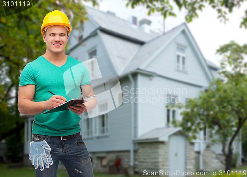 Image of smiling manual worker in helmet with clipboard