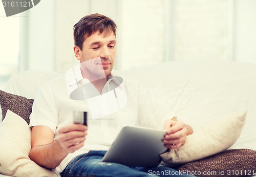 Image of man with tablet pc and credit card at home