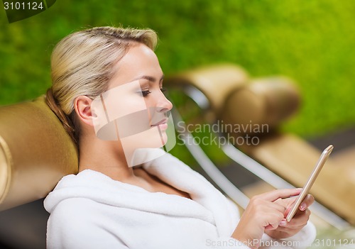 Image of beautiful young woman with smartphone at spa