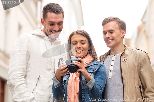Image of group of smiling friends with digital photocamera