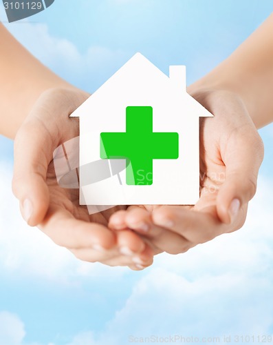 Image of hands holding paper house with green cross
