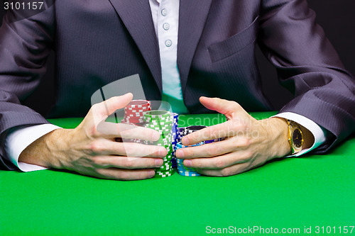 Image of Man with a bunch of chips. Green table