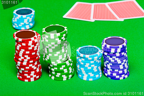 Image of chips on the background of green the table. Cards in the backgro