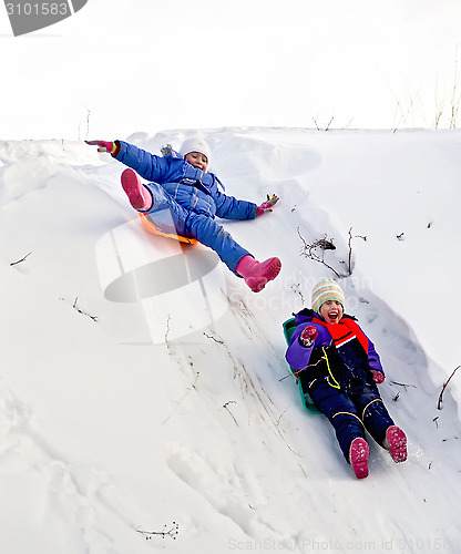 Image of Two girls on sled through the snow to slide