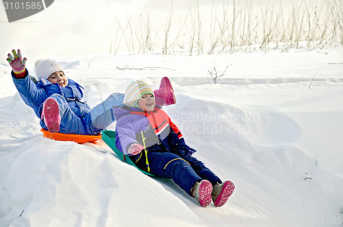 Image of Two little girls on sled through the snow to slide