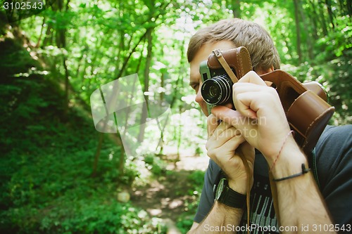 Image of Closeup of young hipster man with digital camera outdoors.