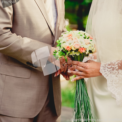Image of mans hand putting a wedding ring on the brides finger
