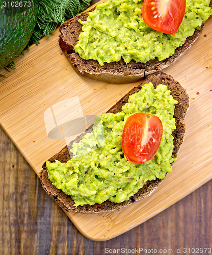 Image of Sandwich with guacamole and tomato on board