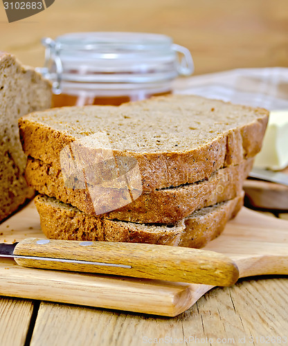 Image of Rye homemade bread with honey and knife on board