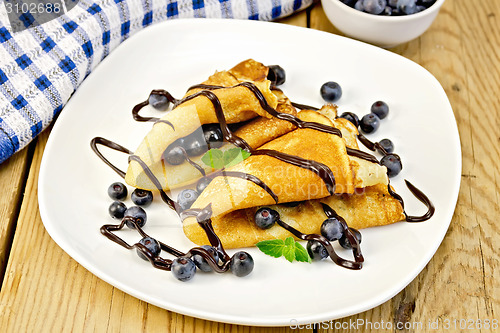 Image of Pancakes with blueberries and chocolate on board
