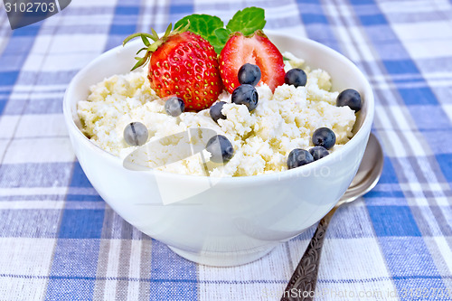 Image of Curd in bowl with strawberries and blueberries on tablecloth