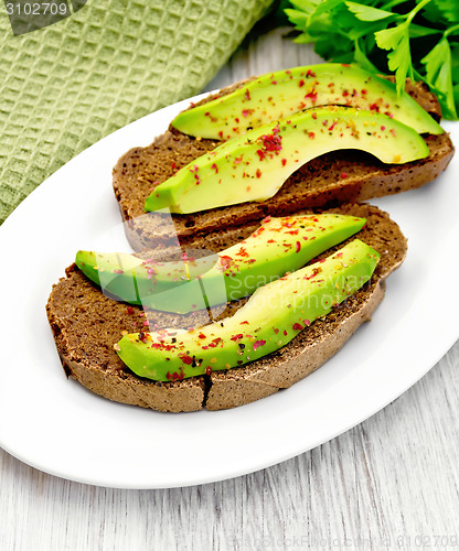 Image of Sandwich with avocado and parsley on light board
