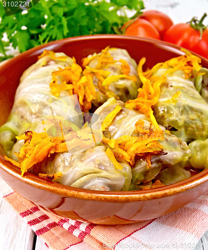 Image of Cabbage stuffed and carrots in ceramic pan on board