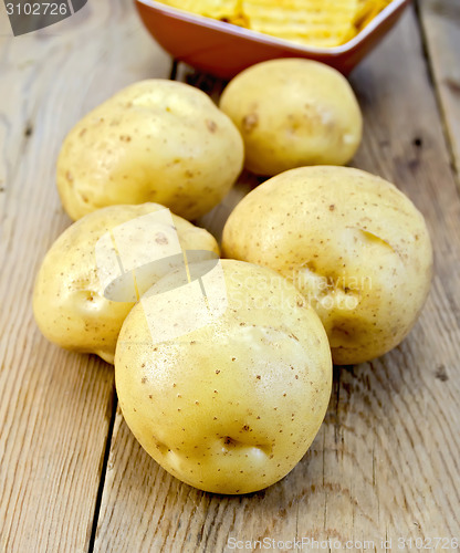 Image of Potatoes yellow and chips on wooden board
