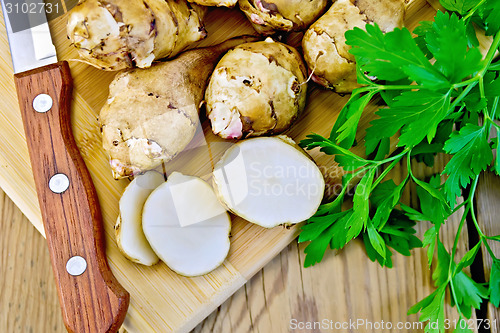 Image of Jerusalem artichokes cut with knife and parsley on board