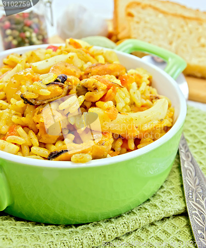 Image of Pilaf with seafood in green pot on napkin