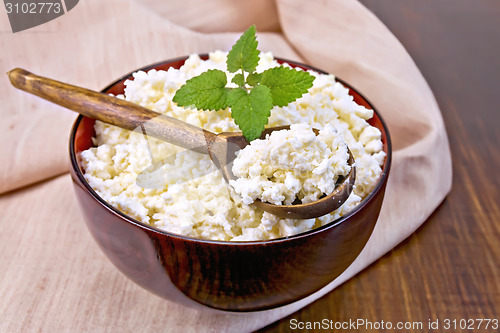 Image of Curd in wooden bowl with spoon on napkin and board