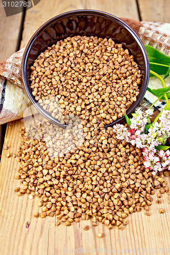 Image of Buckwheat in brown bowl with flower and towel on board