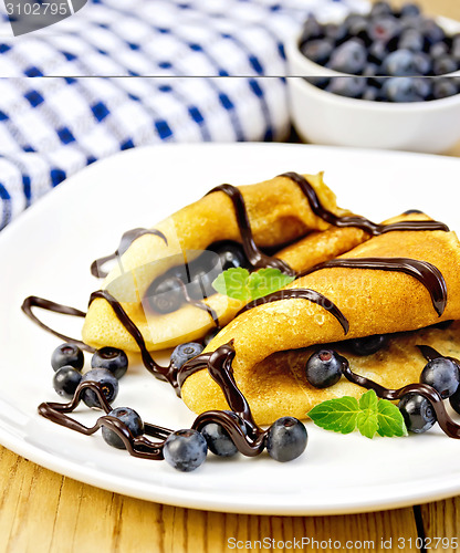 Image of Pancakes with blueberries and chocolate on wooden board