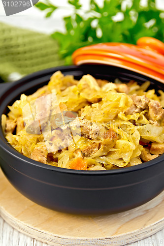 Image of Cabbage stew with meat in black roaster on board