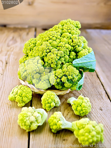 Image of Broccoli green in wicker basket on board