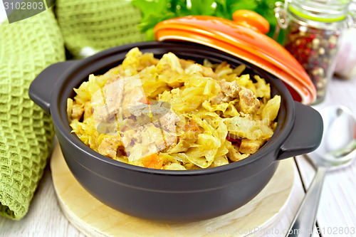 Image of Cabbage stew with meat in black brazier on light board