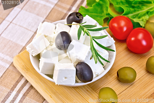 Image of Feta with olives in bowl on fabric and board