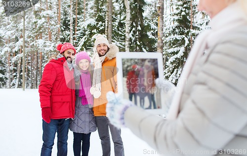 Image of smiling friends with tablet pc in winter forest