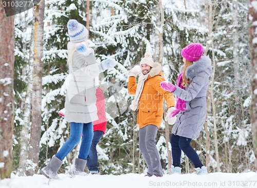 Image of group of happy friends playing snowballs in forest