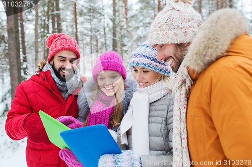 Image of smiling friends with tablet pc in winter forest