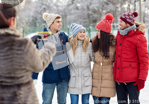 Image of happy friends taking picture with smartphone