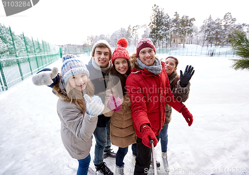 Image of happy friends with smartphone on ice skating rink