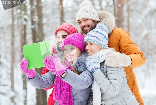 Image of smiling friends with tablet pc in winter forest