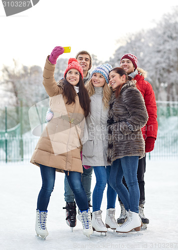 Image of happy friends with smartphone on ice skating rink
