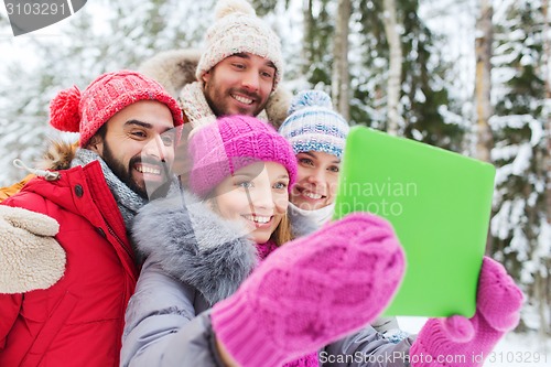 Image of smiling friends with tablet pc in winter forest