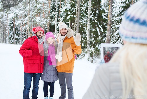 Image of smiling friends with tablet pc in winter forest