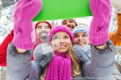 Image of smiling friends with tablet pc in winter forest