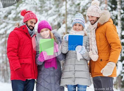 Image of smiling friends with tablet pc in winter forest